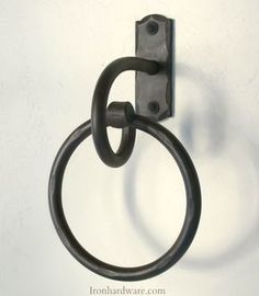 a metal hook on the side of a white wall with a circular ring hanging from it's center