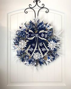 a blue and white christmas wreath hanging on a door with snowflakes around it