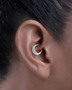 a woman's ear is shown with a small gold hoop on the side of her ear