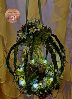 an arrangement of flowers and plants hanging from a chandelier