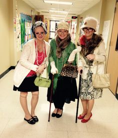 three women are standing in the hallway with their canes and hats on, one is holding an umbrella