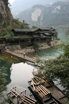 there are many wooden boats docked at the water's edge in front of some buildings