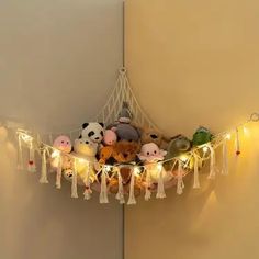 several stuffed animals are hanging from a string with lights strung around them and attached to the wall