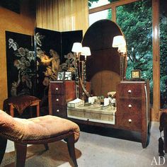 a bedroom with a vanity, mirror and chair in front of a large open window