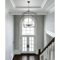 an entryway with a chandelier hanging from the ceiling and hardwood flooring