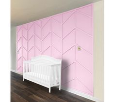 a white crib in front of a pink wall with geometric designs on it and a wooden floor