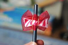 a hand holding a candy cane with a bow on it