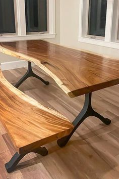 a large wooden table sitting in front of two windows on top of a hard wood floor