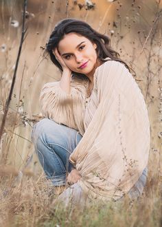 a woman is sitting in the tall grass