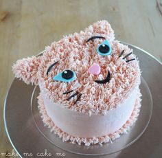 a cake decorated to look like a cat with blue eyes and pink frosting on top