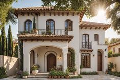 A beautiful Mediterranean style house with a garden in front of it. The house has a white facade with a red roof and a balcony on the second floor. The garden is filled with potted plants and flowers, creating a welcoming atmosphere. The house is situated on a street with a driveway leading up to it. Spanish Hacienda Style Homes, Spanish Style Home Exterior, Residential Facade, Mexican Style Homes, Mediterranean Farmhouse