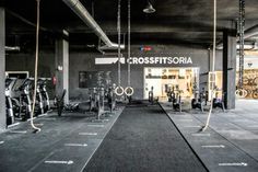 an indoor gym with rows of exercise bikes and ropes hanging from the ceiling, in front of a crossfit store