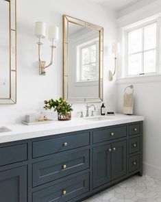 a large bathroom with two sinks and mirrors on the wall, along with blue cabinets