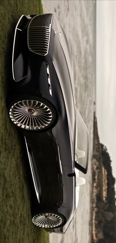 an aerial view of a black sports car parked on the side of a mountain road