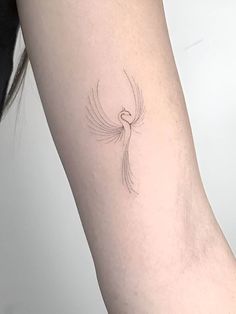 a woman's arm with a small bird tattoo on the left side of her body