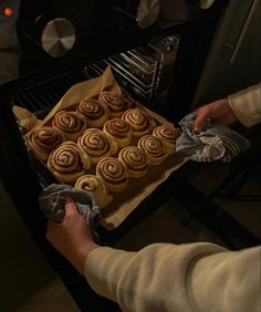 a person pulling out some food from an oven