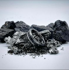 a couple of rings sitting on top of some rocks and silver flakes in front of them