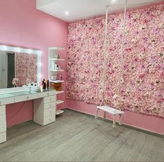 a bathroom with pink walls and flowers on the wall behind the vanity, mirror and stool