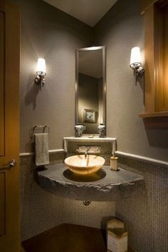 a bathroom sink sitting under a mirror next to a wooden cabinet and wall mounted faucet