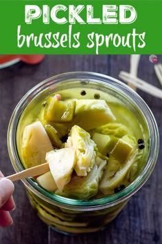 pickled brussel sprouts in a glass jar with a wooden spoon