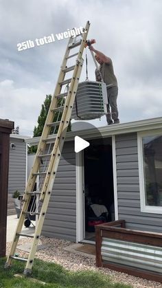 a man standing on top of a ladder next to a house with a bucket in the air