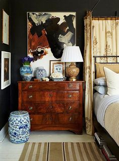 a bed room with a neatly made bed and a painting on the wall above it