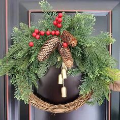 a wreath with pine cones and bells hanging on a door