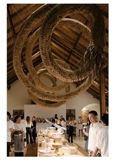 a group of people standing around a table with food on it and hanging from the ceiling