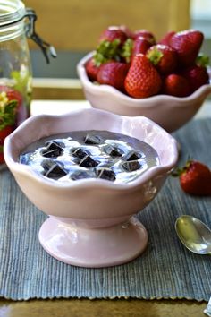 two bowls filled with ice and strawberries on top of a place mat next to mason jars