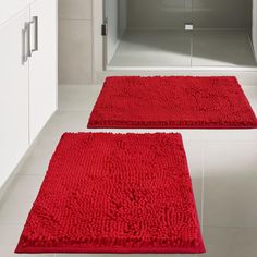 two red rugs on the floor in a bathroom