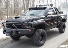 a large black truck parked on the side of a road in front of a house