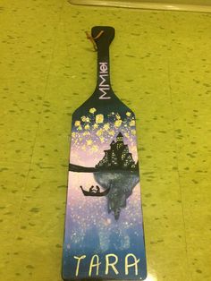 a painted paddle with a boat on it and the name tara written in blue ink