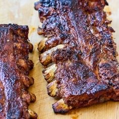 two pieces of meat sitting on top of a wooden cutting board next to each other