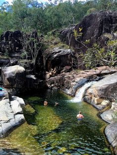 several people swimming in the water near some rocks