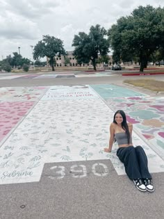 a woman is sitting on the ground in front of a large rug with flowers and numbers