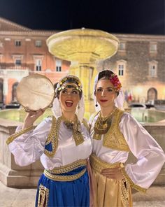 two women dressed in traditional greek costumes posing for the camera