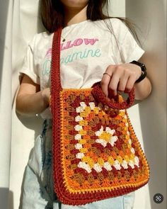 a woman is holding a crocheted purse