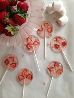 strawberries and marshmallows are arranged on sticks in front of a plate