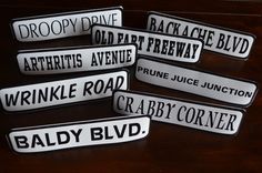 five black and white street signs sitting on top of a wooden table