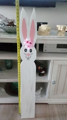 a wooden bunny with a pink bow on it's head standing next to a ruler