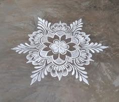 an intricately designed design on the ground with white paint and grey cement in the background