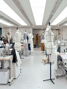 a room filled with lots of white mannequins and sewing machines in it