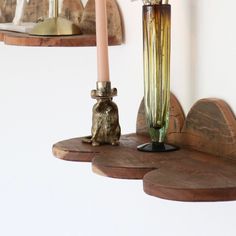 a vase with flowers and two candles on top of some wooden shelves next to each other