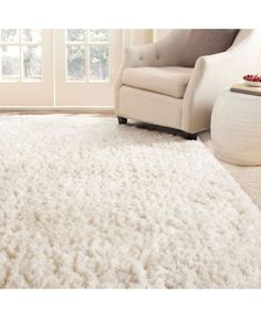 a white rug in a living room with a chair next to it and a window