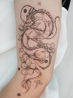 a woman's arm with a dragon and flowers tattoo on the left side of her body