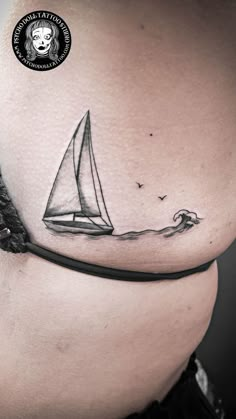 a woman's stomach with a sailboat tattoo on it