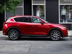 a red mazda cx - 5 parked in front of a store