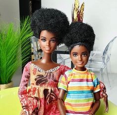 two dolls sitting next to each other on a table