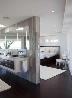 a modern bathroom with wood flooring and large mirror on the wall above the sink