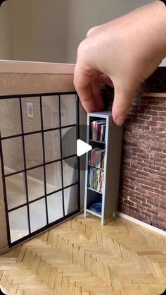 someone is opening the door to their dollhouse bookcase and it's contents